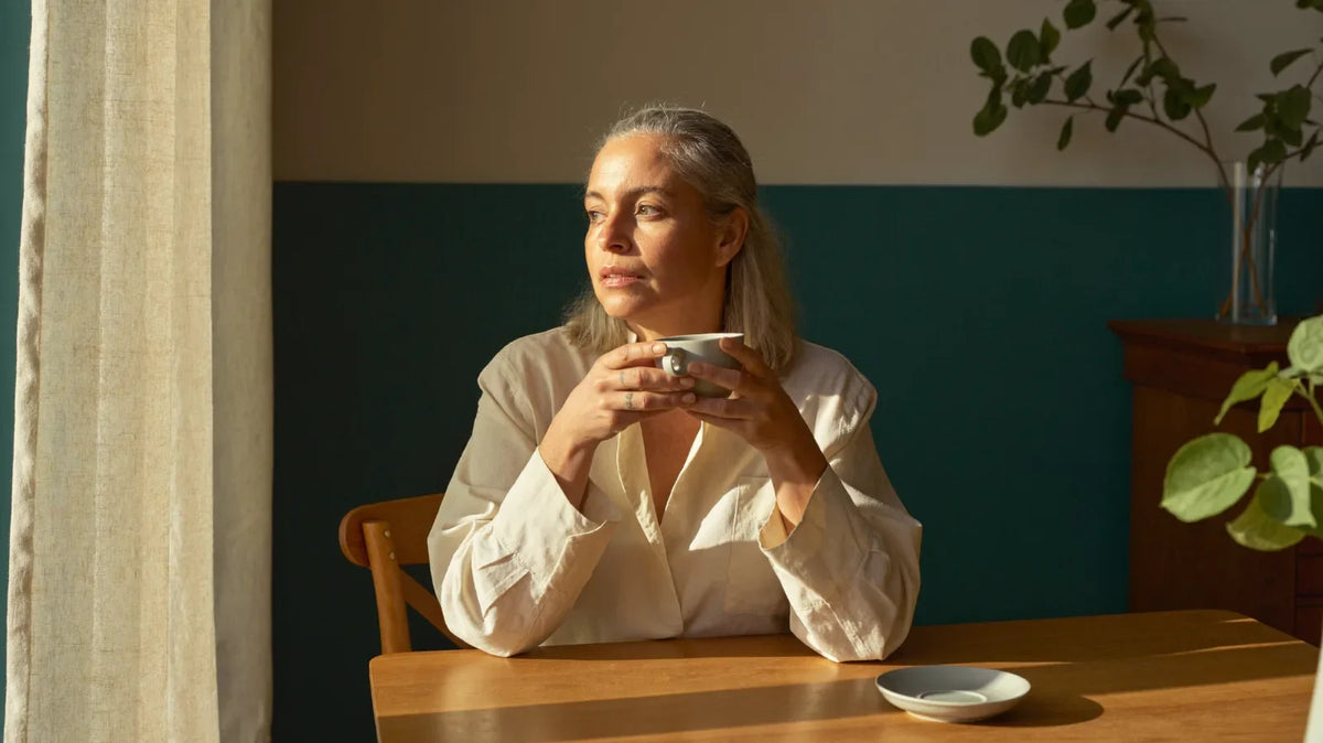 Femme de 50 ans sereine au petit matin — comprendre les 34 symptômes de la ménopause